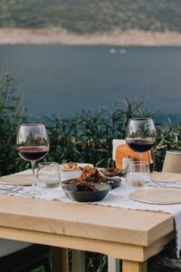 A serene table setting with red wine overlooking a tranquil sea, perfect for romantic dining.