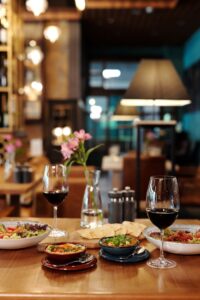 An inviting restaurant table setting featuring ceramic bowls, red wine, and ambient lighting.